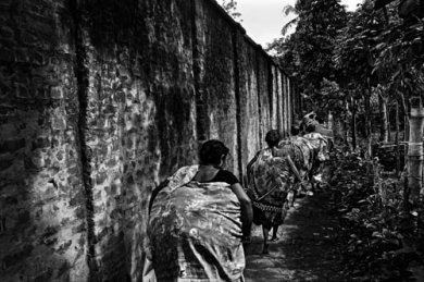 © Gaël TURINE - Inde. Des Bangladaises, passées illégalement en Inde, courent au pied du mur érigé le long de la ville frontalière de Hili. Elles ont acheté des marchandises indiennes (épices, bijoux, produits de beauté, médicaments...) qu’elles revendront au Bangladesh.